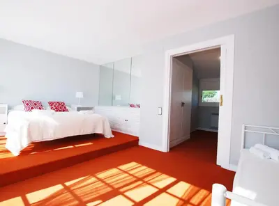 a white bedroom with a white bed and red pillows at Torre Vendrell con Padel in Sant Pere de Vilamajor