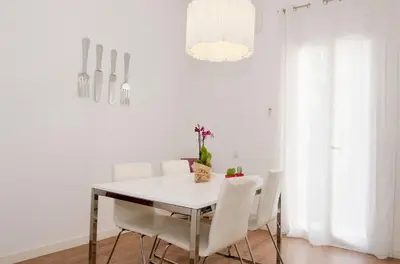 a white dining room with a white table and white chairs at Apartamento Gaudí-Sant Pau in Barcelona