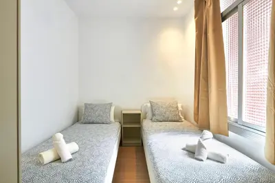 two beds in a room with two windows at Vibrant and modern apartment in Barcelona