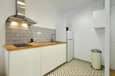 a white kitchen with a sink and a refrigerator at Vibrant and modern apartment in Barcelona