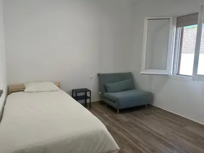 a bedroom with a bed and a blue chair at Holiday Beach Home Rincón del Mar in Cunit