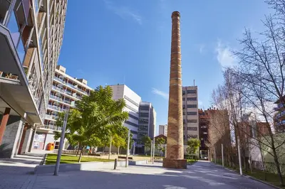 a tall pole in the middle of a city at The Lonely Chimney Apartments in Barcelona