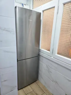 a stainless steel refrigerator in a kitchen with two windows at Apartamento Moderno, amplio y muy cómodo in Terrassa