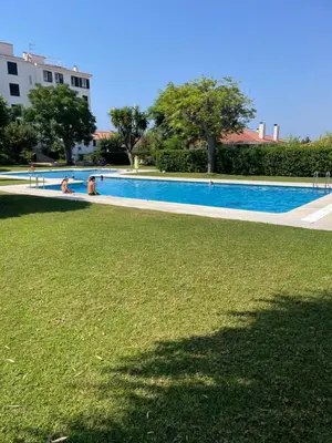 a swimming pool with two people in the grass at Viva Sitges - Sitges View in Sitges