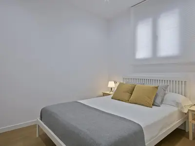 a bed in a white room with a window at La Terraza de Badalona in Badalona