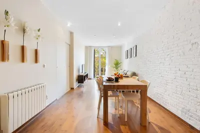 a dining room with a table and a white brick wall at Lodging Apartments Entenca in Barcelona