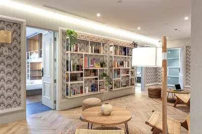 a living room with a table and bookshelves at Weflating Boutique Hostel in Barcelona