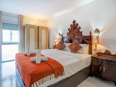 a bedroom with a large bed with a wooden headboard at Casa Rainbow by Hello Homes Sitges in Sitges