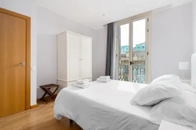 a white bedroom with a large bed and a window at Flateli Pelayo H3 in Barcelona