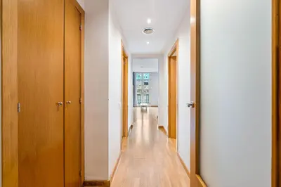 a hallway with wooden doors and a long hallway with wooden floors at Flateli Pelayo H3 in Barcelona