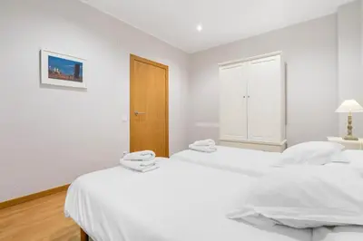 two beds in a bedroom with white walls and wooden floors at Flateli Pelayo H3 in Barcelona