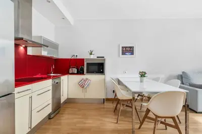 a kitchen with a dining table and a kitchen with red walls at Flateli Pelayo H2 in Barcelona