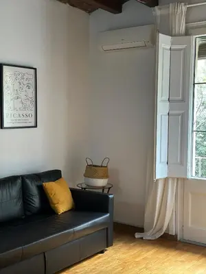 a living room with a black couch and a window at Dudu life in Barcelona