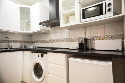 a kitchen with a washing machine and a microwave at Casa a pasos de Las Ramblas in Barcelona