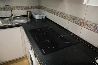 a black stove top in a kitchen with a sink at Casa a pasos de Las Ramblas in Barcelona