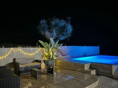 a swimming pool at night with a palm tree and lights at Casa con piscina uso privado in Cunit