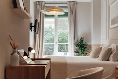 a bedroom with a bed and a window with a laptop on a desk at Casa Dorada in Barcelona