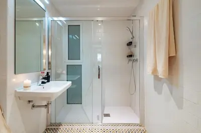 a white bathroom with a shower and a sink at Casa Dorada in Barcelona