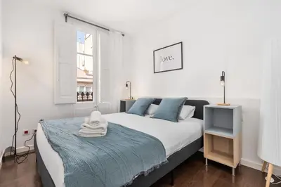 a white bedroom with a large bed and a window at Enrique Granados Apartment in Barcelona