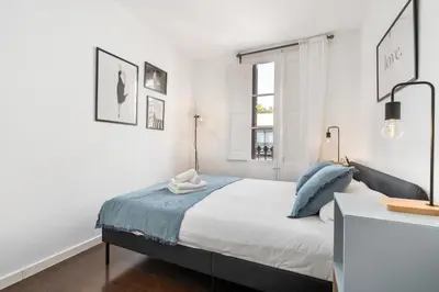 a white bedroom with a bed and a window at Enrique Granados Apartment in Barcelona