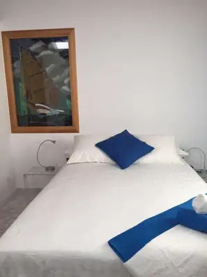 a white bed with blue pillows and a mirror at House Seaviews Barcelona 22Km in Cabrils