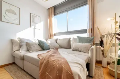 a white couch in a living room with a window at Penthouse with Private Terrace & Pool Access in Cornellà de Llobregat