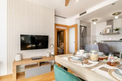 a living room with a table and a television at Penthouse with Private Terrace & Pool Access in Cornellà de Llobregat
