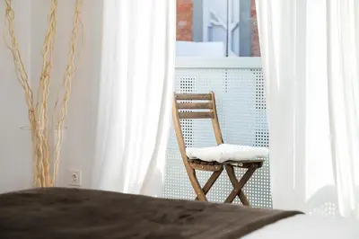 a wooden chair sitting in a bedroom next to a window at Glasir Homes Barcelona in Barcelona