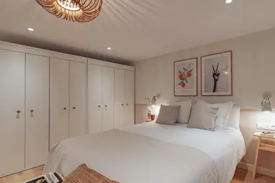 a bedroom with a large bed with white cabinets and a chandelier at Casa Lennon in Barcelona