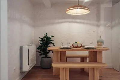 a dining room table with a bench and a television at Casa Lennon in Barcelona
