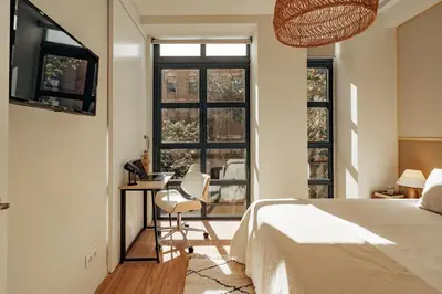 a bedroom with a bed and a desk and windows at Casa Macaya in Barcelona