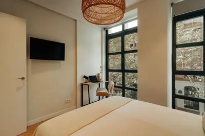 a bedroom with a bed and a tv and windows at Casa Macaya in Barcelona
