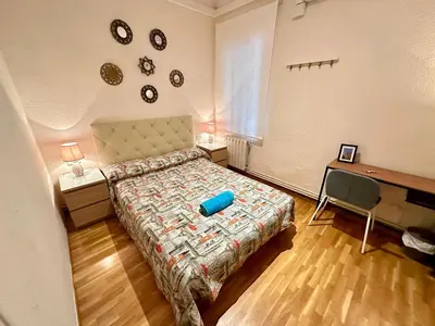 a bedroom with a bed and a desk with a television at Habitaciones acogedoras en Aragón in Barcelona