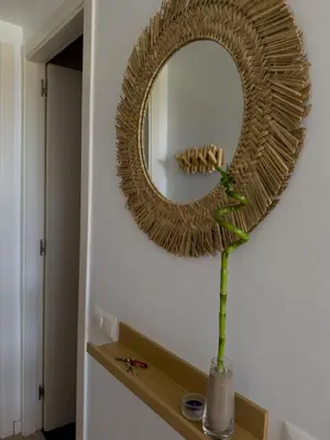 a mirror on a wall with a vase with a plant at Apartamento en la playa in Castelldefels