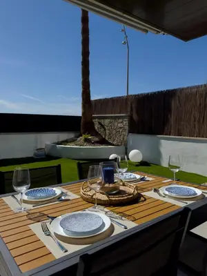 a wooden table with plates and wine glasses on it at Apartamento en la playa in Castelldefels