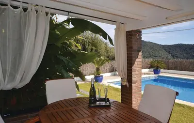a dining table with a view of a swimming pool at Lovely Home In St Cebrià De Vallalta in Sant Cebrià de Vallalta
