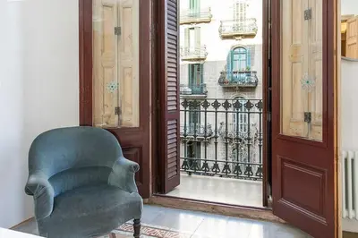 a green chair sitting in a room with a window at Canela Homes BARCELONA CONCEPCIÓ in Barcelona