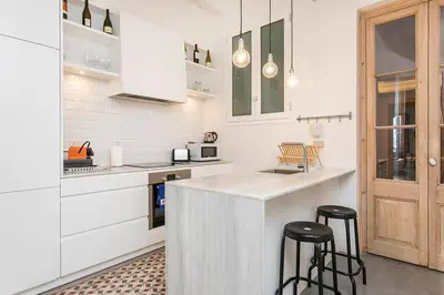 a kitchen with white cabinets and black stools at Canela Homes BARCELONA CONCEPCIÓ in Barcelona
