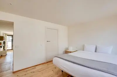 a white bedroom with a large bed and wooden floors at Urban Flats Park Guell in Barcelona