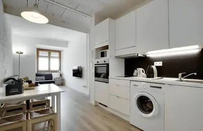a kitchen with white cabinets and a washing machine at Urban Flats Park Guell in Barcelona