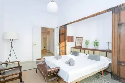 a bedroom with a large white bed and a chair at Canela Homes BARCELONA CASA SERRA in Barcelona