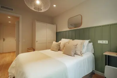 a bedroom with a large white bed with a tv on the wall at Casa Tila in Barcelona