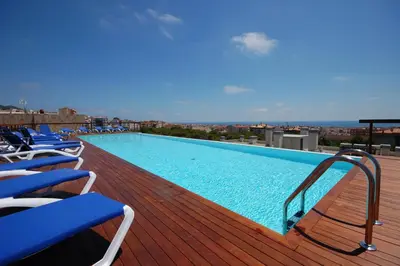 a large swimming pool on a deck with chairs at Resort Sitges Apartment in Sitges