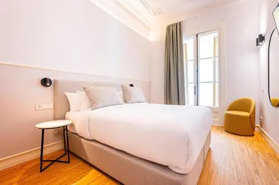 a bedroom with a large white bed and a chair at Sweett - La Gran Via in Barcelona