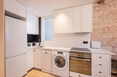 a kitchen with white cabinets and a washing machine at Sweett - Urgell Eixample in Barcelona