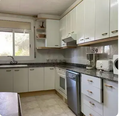 a kitchen with white cabinets and stainless steel appliances at villa 7 personnes 45 mn Barcelone vue sur Montserrat in Vacarisas