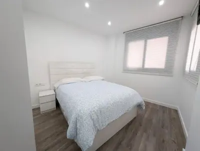 a white bedroom with a bed and two windows at New flat in the centre, 10 min from BCN Airport in Cornellà de Llobregat