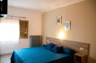 a bedroom with a blue bed and a window at Hostal Montserrat in Montseny