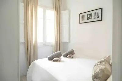 a white bed in a white room with a window at SAGRADA FAMILIA SUN Nos preocupa su seguridad in Barcelona
