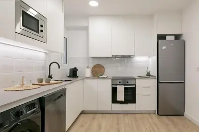 a white kitchen with a stove and a refrigerator at Cathedral Ramblas Apartment in Barcelona